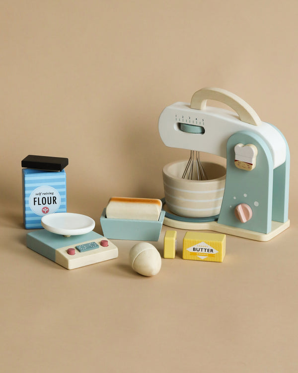 A Wooden Baking Set displayed on a beige background, featuring a stylish mint green stand mixer, containers labeled flour and butter, a wooden bowl, and various baking ingredients and utensils.