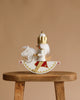 The Christian Ulbricht Collectible Wooden Nutcracker - Rider King, wearing a crown and gold-red accents, sits on a white rocking horse atop a wooden stool against a plain beige background.