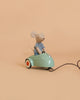 A small Maileg mouse from the Maileg LouiMax and Stella Adventure Set, dressed in a striped shirt, sits in a mint green Maileg car with a pull string against a plain beige background—an adorable addition to any Little Brother and Sister Mice collection.