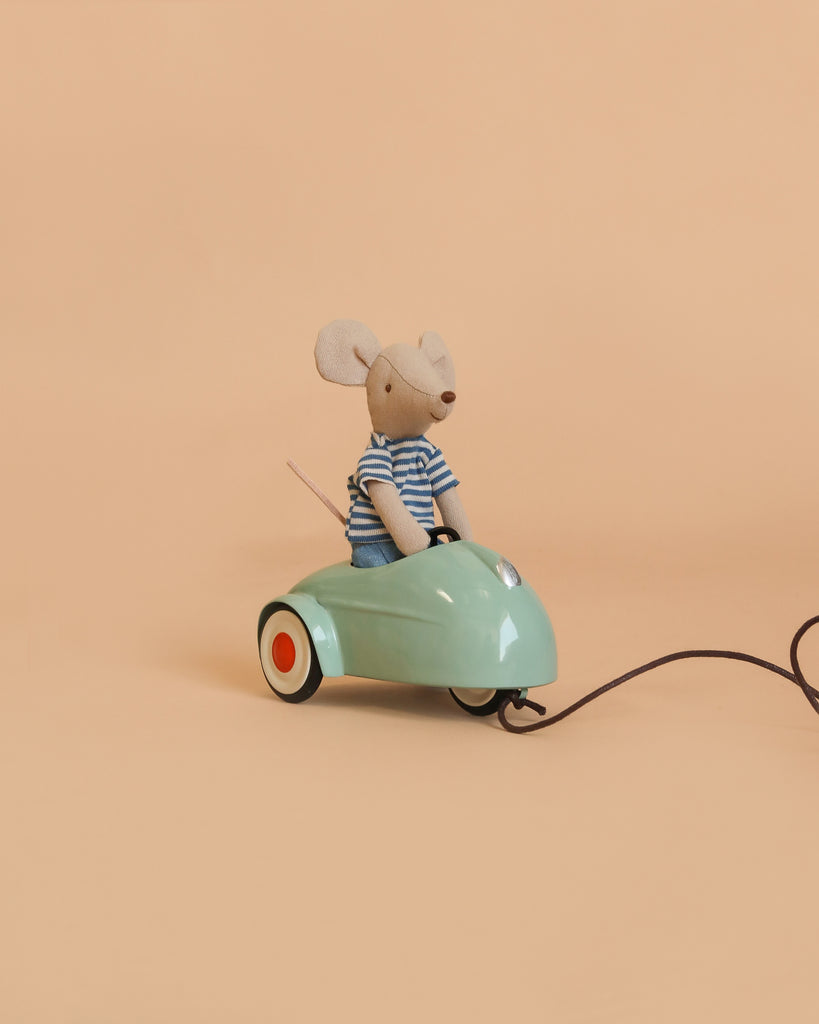A small Maileg mouse from the Maileg LouiMax and Stella Adventure Set, dressed in a striped shirt, sits in a mint green Maileg car with a pull string against a plain beige background—an adorable addition to any Little Brother and Sister Mice collection.
