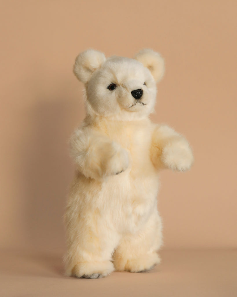 The Polar Bear Cub Stuffed Animal, with its soft fur and black nose, stands upright against a beige background. Hand-sewn by skilled artisans, it boasts realistic features that captivate any admirer.