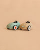 Two small toy cars from the Maileg LouiMax and Stella Adventure Set—one light blue and one beige—are positioned side by side on a beige background. Both feature white wheels with black and red details, along with visible front license plates, making them perfect for your Maileg mice to take Little Brother and Sister Mice on delightful adventures.