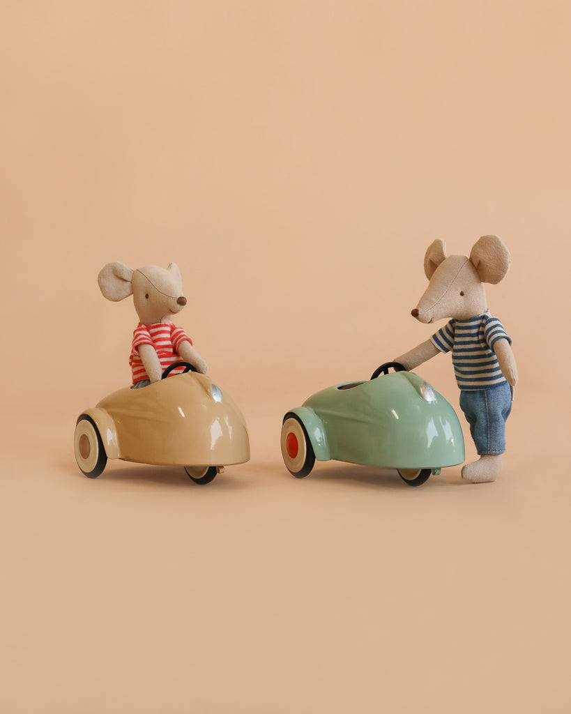 Two Maileg mice from the LouiMax and Stella Adventure Set—dressed in striped shirts—are pictured, with one seated in a beige Maileg car and the other standing beside a green toy car, all set against a plain beige background.