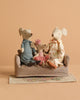 The Maileg Family Set sits together on a Mouse Couch placed on a Maileg Flower Rug, against a plain beige background.