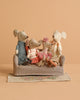 The Maileg Family Set features four mice in colorful outfits sitting on a mouse couch, arranged on a patterned flower rug against a plain beige backdrop.