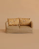 The Maileg Living Room Set features a small beige plaid couch with two yellow floral cushions, ideal for Mouse Furniture or displaying a Maileg Miniature Tea Set against a plain beige background.