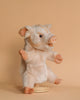 A Pig Puppet stands upright against a beige background, resting on a wooden base. It features light pink fur with orange-tipped ears and realistic details, including prominently highlighted round eyes and snout.