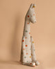 Against a beige background sits the Maileg Large Giraffe, a plush safari companion known for its minimalist design. This cream-colored giraffe is adorned with colorful polka dots in shades of orange, blue, and brown and features long legs and a simple face.