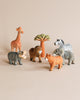 A collection of colorful hand-carved animal toys including a giraffe, elephant, lion, zebra, and Hand Carved Wooden Cheetah, displayed in front of a small wooden tree on a beige background.