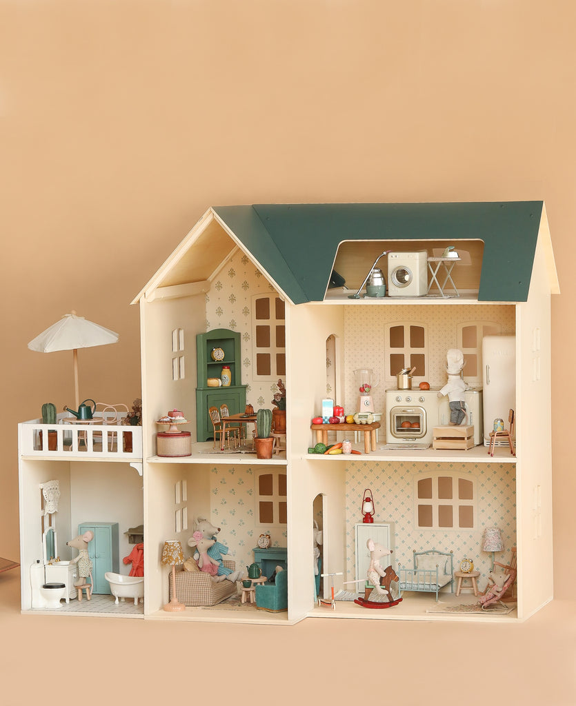 The Maileg Fully Furnished Dollhouse Set + Surprise Gift features multiple rooms, charming dollhouse furniture, small animal figurines, a miniature bathroom, and a rooftop patio with umbrella—all set against a plain beige background.