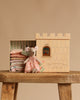The Maileg Princess Fairytale Set features a mouse in a pink dress sitting before a castle-shaped toy box labeled "The Princess Mouse and the Pea," with folded doll clothes inside, all displayed on a wooden stool.