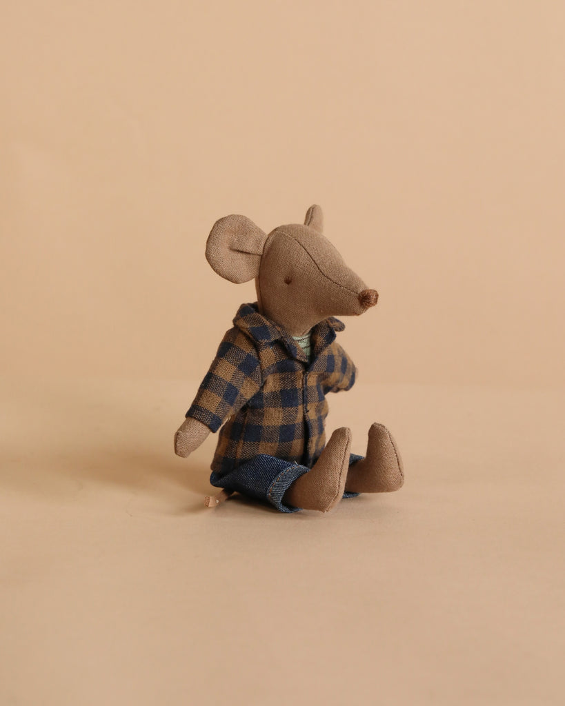 The Maileg Dad Mouse - Light Brown is a small, soft cotton mouse wearing a blue and brown plaid shirt and blue pants, sitting upright on a plain beige surface with a matching beige background.