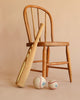 A Foam Baseball Bat + Baseball + Softball Set, arranged with the bat leaning against a wooden chair and two soft baseballs on the floor in front, all set against a beige background—perfect for safe indoor play.