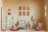 The Maileg Fully Furnished Dollhouse Set + Surprise Gift includes two toy mice (one on a rocking horse, one on a rocking chair), plus bed, wardrobe, scooter, red lantern, lamp, clock, and a four-pane window with patterned wallpaper.