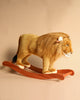 A Stuffed Animal Lion Rocker with a realistic mane stands on an artisan crafted wooden rocking base, against a light brown background. The lion toy appears majestic and lifelike.
