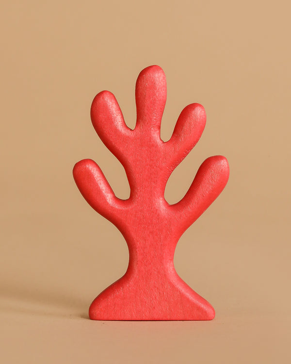 The Handmade Holzwald Red Coral, an abstract tree-shaped toy with rounded branches, stands upright against a plain beige background.