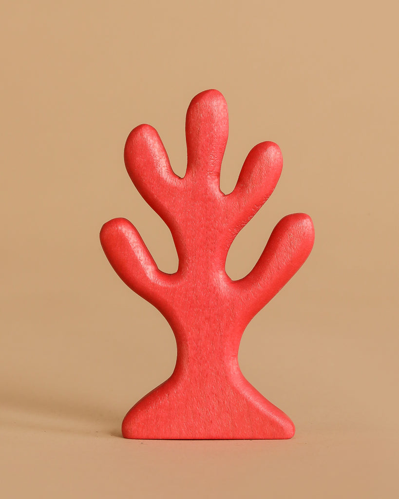 The Handmade Holzwald Red Coral, an abstract tree-shaped toy with rounded branches, stands upright against a plain beige background.