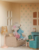Two plush toy mice in knitted outfits sit on a checkered couch inside the Maileg Fully Furnished Dollhouse Set + Surprise Gift, surrounded by cozy furniture, a tea set, and florally wallpapered pastel living room accessories.