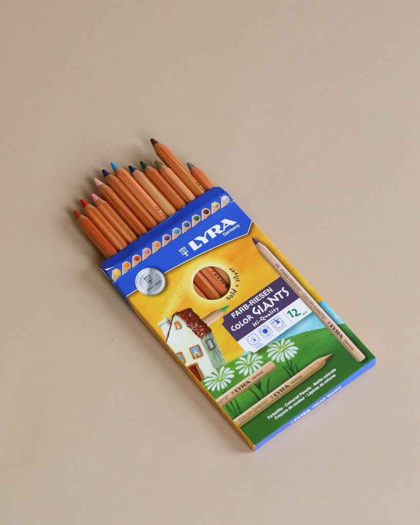 A box of Lyra Color Giants Unlacquered Pencils - 12 Assorted Colors, with 12 assorted colored pencils partially visible, on a light beige background. The box features a vibrant, colorful illustration of a landscape.