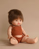 A Minikane Clothed Standing Doll (14.5") - Julian with lifelike features, dressed in a brown ribbed tank top and matching shorts. This anatomically correct doll has short brown hair and is seated against a plain beige background. Its eyes are open, and its hands rest on its legs, emitting a subtle vanilla scent.