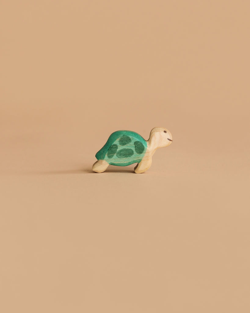 A Handmade Holzwald Sea Turtle, Small, with a green shell and beige body, is displayed on a plain light brown background, inviting open-ended play.