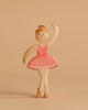 The Handmade Holzwald Ballerina, with a pink tutu and bun, stands en pointe against a plain beige background, smiling warmly—an ideal toy to spark imaginative play.
