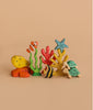 Handmade Holzwald Sea Turtle and other colorful wooden toys—like a yellow fish, clownfish, angelfish, blue starfish, and coral—are arranged on a beige background.