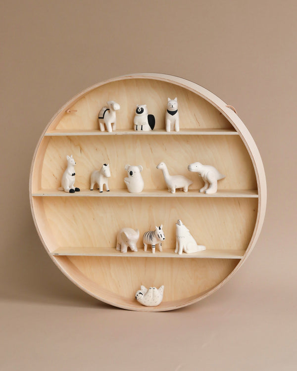 A Ferm Living Round Hanging Shelf displaying a collection of small, white animal figurines, including a panda, rabbits, polar bears, and more, each on separate tiers against a beige background.
