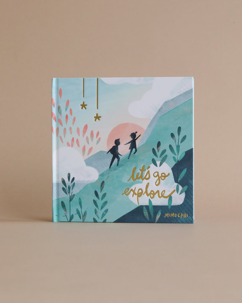 The "Newborn Gift Set - Blue" is displayed with an illustrated book cover featuring two people walking on a mountain, surrounded by plants, clouds, and a pink sun on a beige background—creating a charming scene.