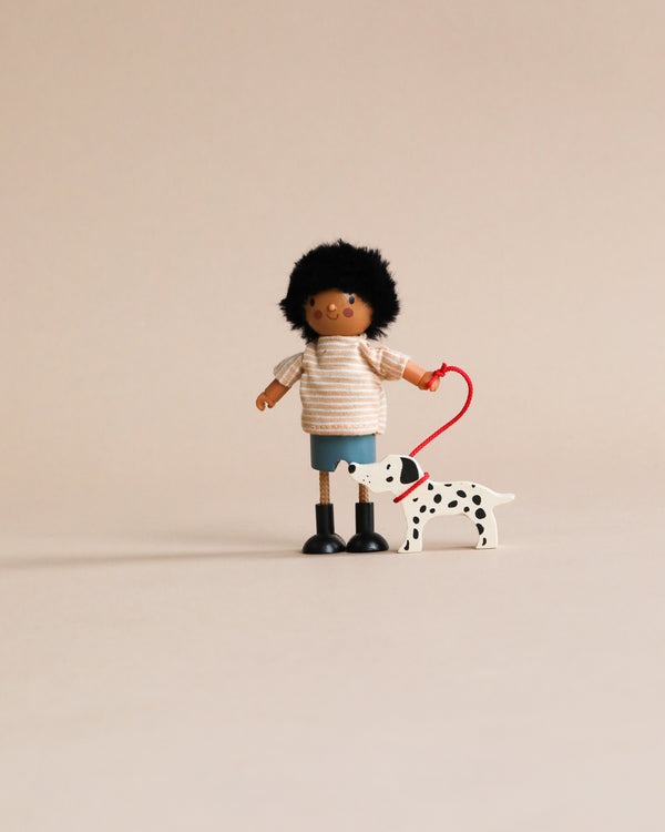A toy figure of Mr. Forrester with his Dog, holding a red leash attached to a small wooden Dalmatian dog against a plain beige background.