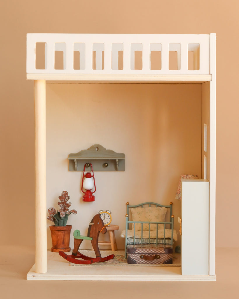 Create a cozy dollhouse scene with the Maileg Bonus Room Bedroom Set, featuring a miniature bed, rocking horse, clock, potted plant, lantern on a shelf, and suitcase on a rug—perfect for charming dollhouse decor.