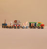 Konges Sloejd Wooden Animal Train featuring colorful beechwood cars carrying circus animals—a rabbit, lion, elephant, and giraffe—against a plain beige background. This charming magnetic train set is perfect for imaginative play.