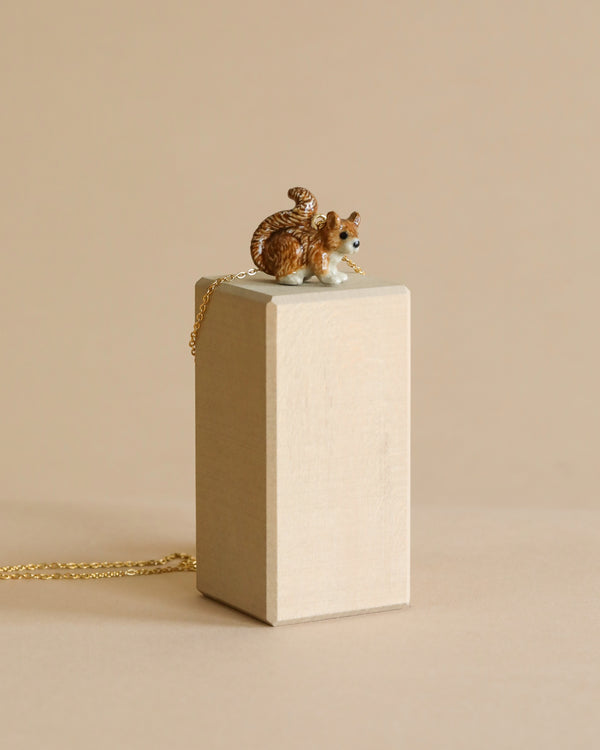 A detailed Squirrel Necklace with a textured fur pattern and 24k gold plated chain sits atop a cream-colored rectangular box against a neutral background.
