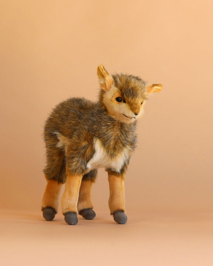 An Antelope Stuffed Animal stands upright on a light tan background. Expertly crafted in the style of handmade plush animals, this toy features soft brown, tan, and white fur with gray hooves and a small smile on its face.