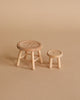 Two small, round, wooden stools with button-like tops are placed on a light brown surface. One stool is slightly larger than the other, both with simple, rustic designs and short, sturdy legs. The background is a matching light beige color—perfect for a charming Maileg Table & Stool Set, Mouse.