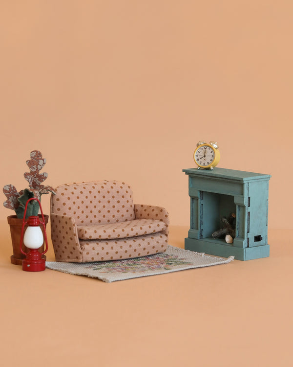 The Maileg Family Room Set features a polka-dot armchair, sofa bed, potted plant, red lantern, small rug, blue fireplace, and yellow clock—ideal mouse dollhouse furniture displayed on a plain beige background.