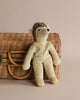 A plush Senger Naturwelt stuffed animal - Hedgehog handmade in Germany in a soft beige color, seated against a woven wicker basket on a plain beige background. The stuffed animal appears soft with a content facial expression.