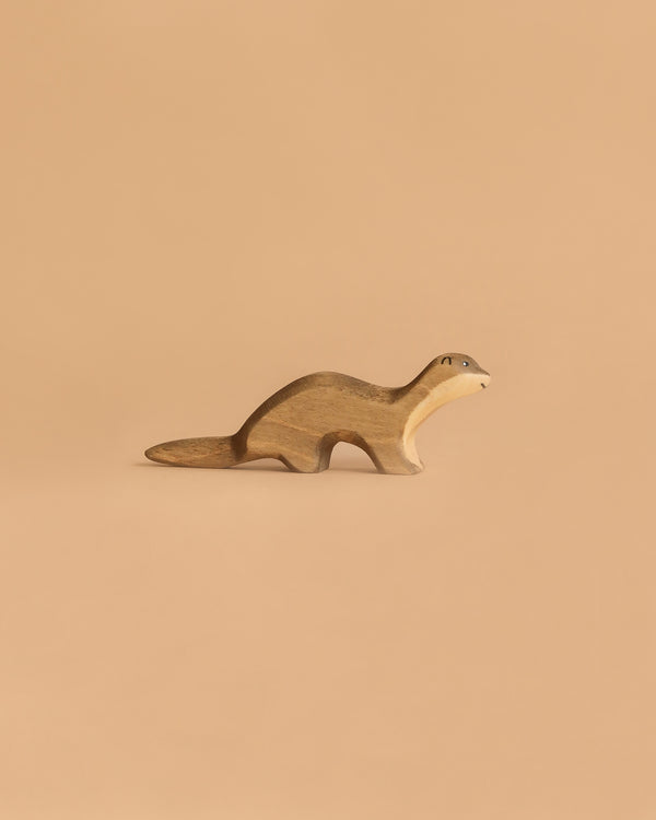 The Handmade Holzwald Otter is a small, handmade wooden animal figurine with a smooth finish and simple painted features, resting against a solid light brown background and capturing the charming style of Holzwald wooden toys.