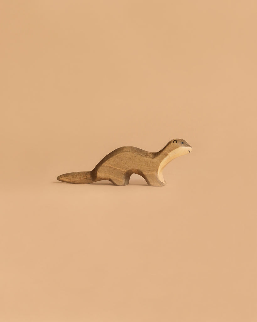 The Handmade Holzwald Otter is a small, handmade wooden animal figurine with a smooth finish and simple painted features, resting against a solid light brown background and capturing the charming style of Holzwald wooden toys.