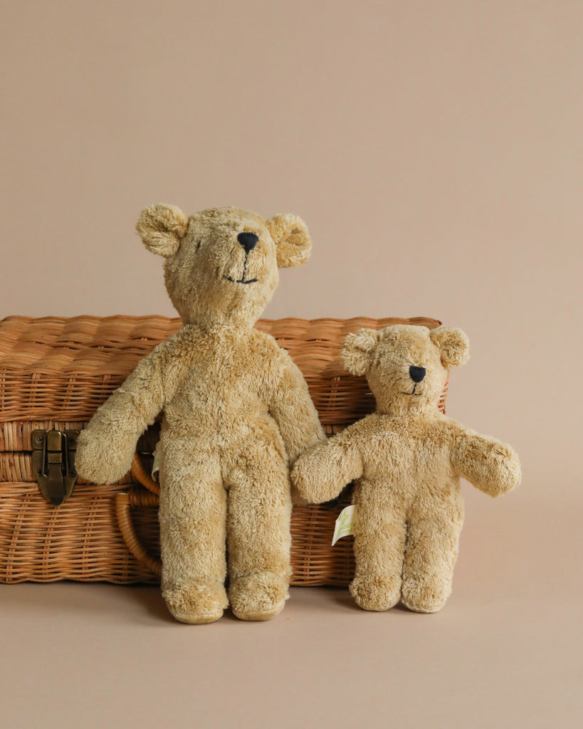 Two Senger Naturwelt Stuffed Animal - Bears, one large and one small, leaning against a wicker picnic basket with a neutral beige background.