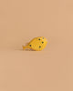 The Handmade Holzwald Pufferfish is a small, yellow wooden toy with black spots and a simple design, displayed on a light brown background—a charming example of sustainable craftsmanship.