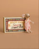 The Maileg Little Sister Mini House Set features a mouse in pink gingham beside a decorative “Mouse Race” matchbox with a vintage race car illustration on a tan background.