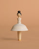 The Sabo Concept Wooden Ballerina is a handmade spinning top crafted to look like a woman with a bun and a white skirt, set against a beige background.