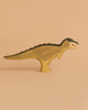 The Handmade Holzwald Dinosaur Set features upright wooden dinosaur toys painted in brown and black, set against a beige backdrop—an ideal example of sustainable craftsmanship.