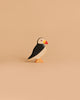 The Handmade Holzwald Puffin Bird is a small wooden toy with black, white, and orange details, standing upright on a beige background—a charming example of sustainable craftsmanship.