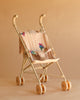 The Konges Sloejd Tulle Doll Stroller - Rainbow Star features a quilted beige seat adorned with colorful rainbow star patterns, curved handles, and four pairs of double wheels with yellow accents, all set against a plain beige background.