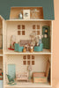 The Maileg Fully Furnished Dollhouse Set + Surprise Gift features three rooms: a laundry with washer and iron, a living room with sofas, two mice, lamp, and a nursery with crib, rocking chair, and toy chest.