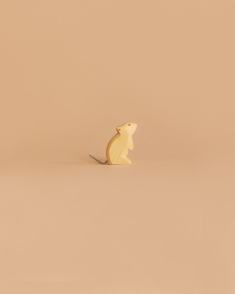 The Handmade Holzwald Mouse - Standing, a small wooden figurine with a thin tail, is displayed on a plain light beige background.