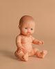 The Minikane Vintage Baby Doll (13") - Lily, with light skin, blue eyes, and molded hair, sits nude on a light beige background with its legs spread and arms extended forward. Clothing sold separately. Made in Spain.