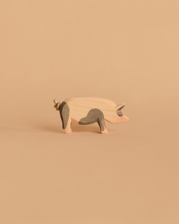 The Ostheimer Spotted Pig - Head High, a handcrafted wooden toy with gray patches, stands on a beige background—perfect for imaginative play and inspired by classic Ostheimer quality.